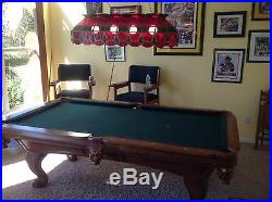Slightly used pool table with the sticks, balls, and cue rack