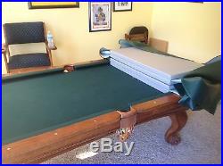 Slightly used pool table with the sticks, balls, and cue rack